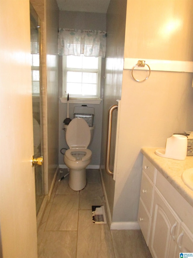 full bathroom featuring a shower with shower door, vanity, and toilet