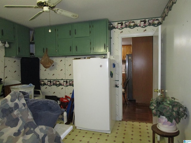 kitchen featuring light floors, green cabinetry, freestanding refrigerator, and wallpapered walls