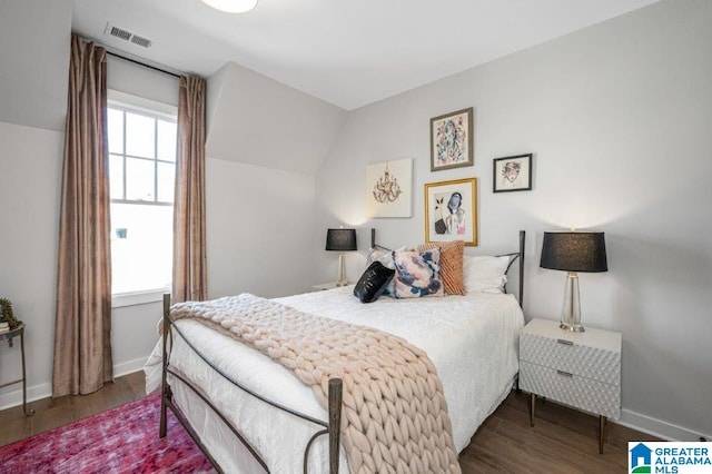 bedroom with lofted ceiling, visible vents, dark wood finished floors, and baseboards