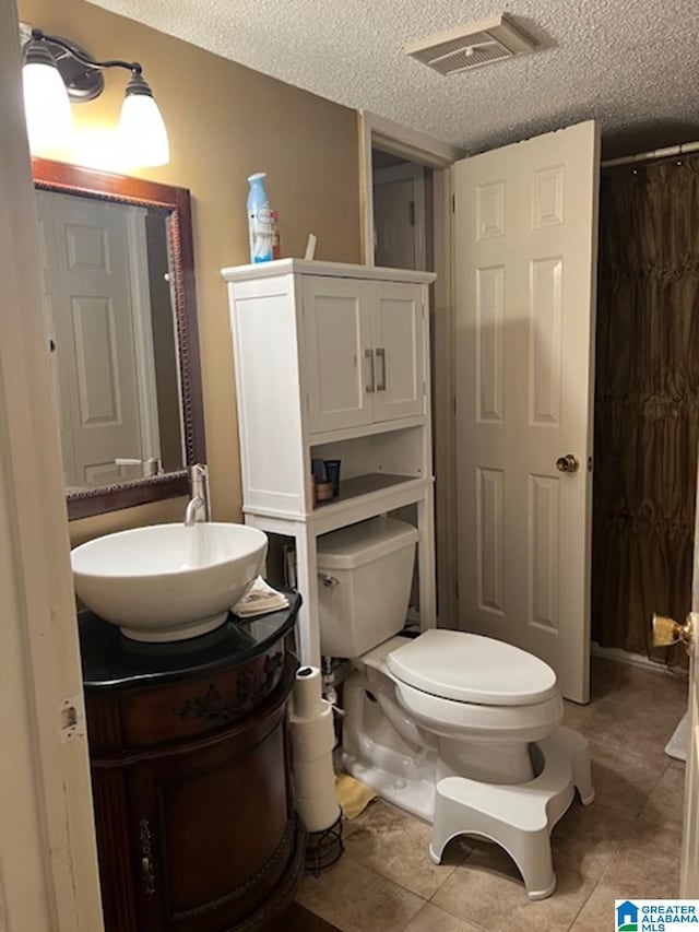 full bath featuring visible vents, a shower with shower curtain, toilet, vanity, and a textured ceiling