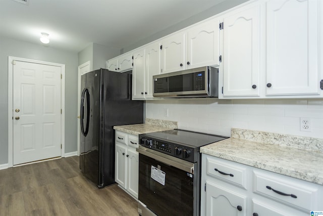 kitchen featuring freestanding refrigerator, stainless steel microwave, range with electric stovetop, and white cabinetry