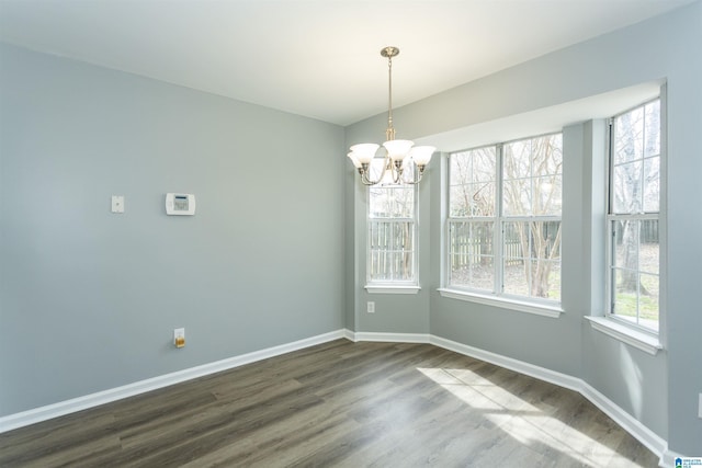 unfurnished dining area featuring a chandelier, dark wood finished floors, and baseboards