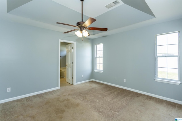 spare room with carpet floors, baseboards, visible vents, and a wealth of natural light