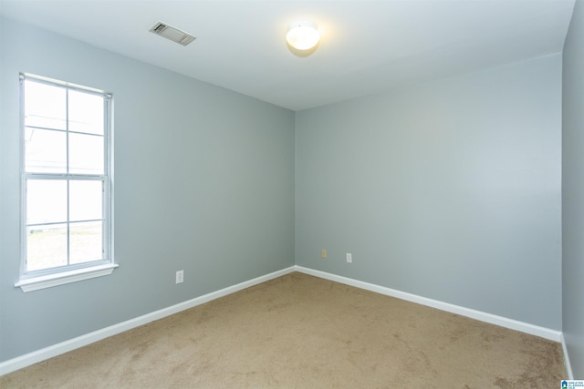 unfurnished room with baseboards, visible vents, and light colored carpet