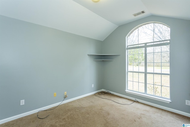 empty room with carpet, visible vents, vaulted ceiling, and baseboards