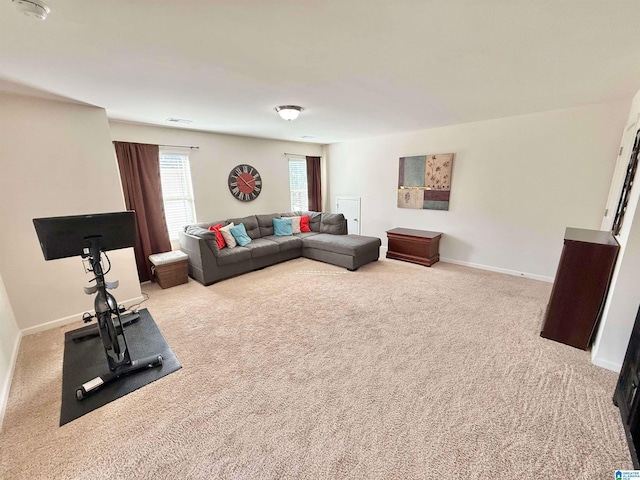 living area with light colored carpet, visible vents, and baseboards