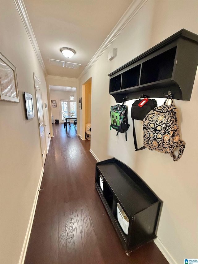 mudroom with dark wood-style floors, crown molding, and baseboards