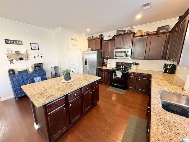 kitchen featuring stainless steel appliances, light stone counters, visible vents, and a center island