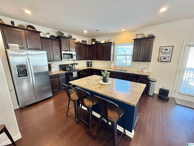 kitchen with a center island, stainless steel appliances, dark wood-type flooring, a sink, and dark brown cabinetry