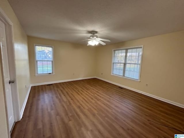 unfurnished bedroom featuring dark wood-style floors, baseboards, and a ceiling fan