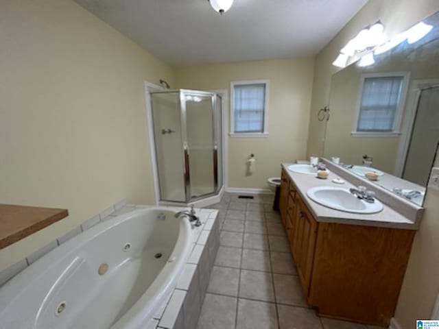 bathroom featuring double vanity, toilet, a tub with jets, tile patterned flooring, and a sink