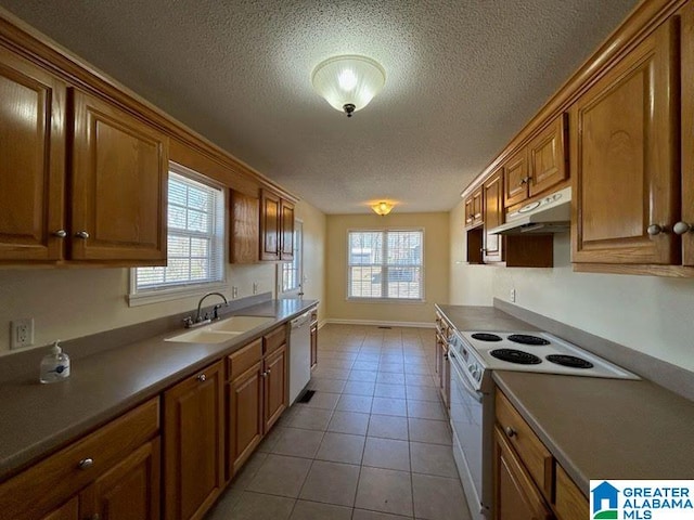 kitchen with brown cabinetry, white appliances, a sink, and under cabinet range hood