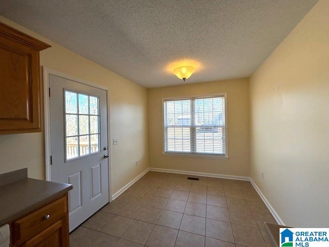 entryway featuring light tile patterned floors, baseboards, visible vents, and a textured ceiling