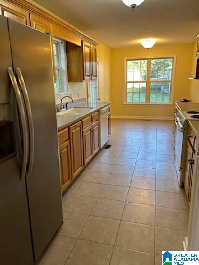 kitchen with white appliances, light tile patterned floors, baseboards, light countertops, and a sink