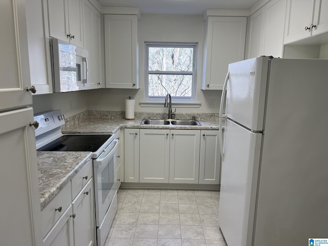 kitchen with white appliances, light tile patterned floors, light countertops, white cabinetry, and a sink