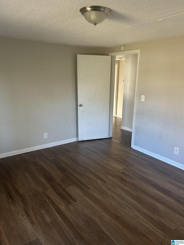 empty room featuring baseboards, dark wood finished floors, and a textured ceiling