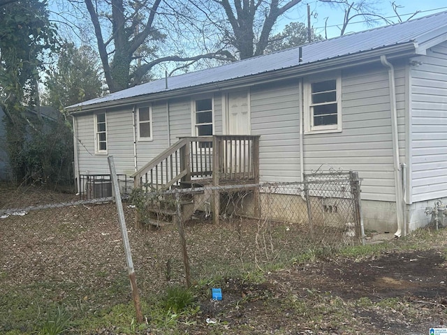 back of house featuring crawl space, fence, and metal roof