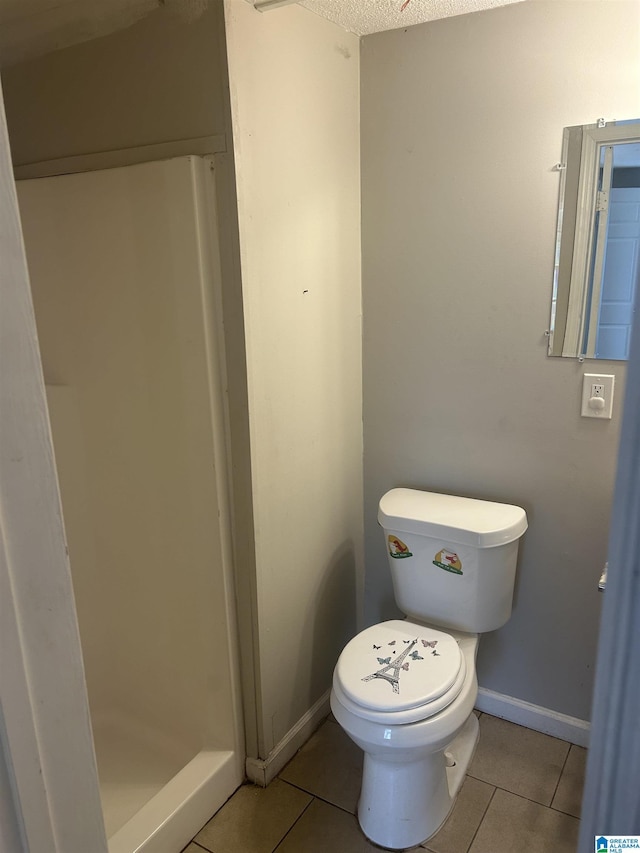 bathroom with tile patterned flooring, toilet, a textured ceiling, and baseboards