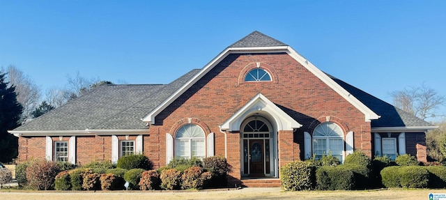 view of front of house with brick siding and a shingled roof