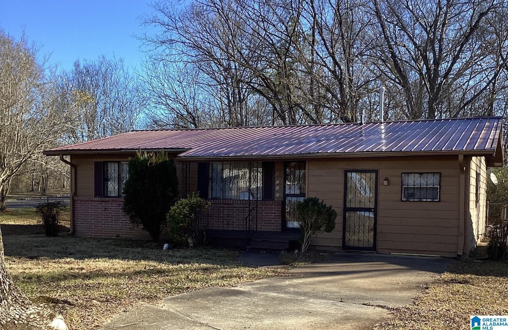 ranch-style home featuring metal roof and brick siding