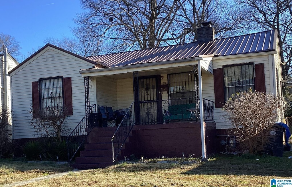 view of front of property with metal roof, a porch, and a chimney