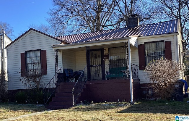 view of front of property with metal roof, a porch, and a chimney