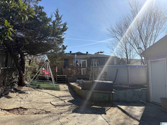 exterior space featuring a playground, fence, a wooden deck, and a patio