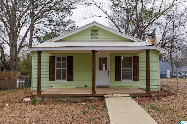 bungalow-style home featuring metal roof, a porch, and fence