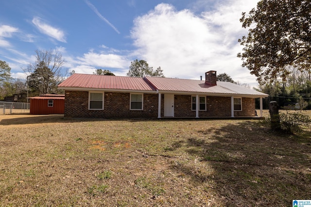 ranch-style house with brick siding, metal roof, a chimney, and a front lawn