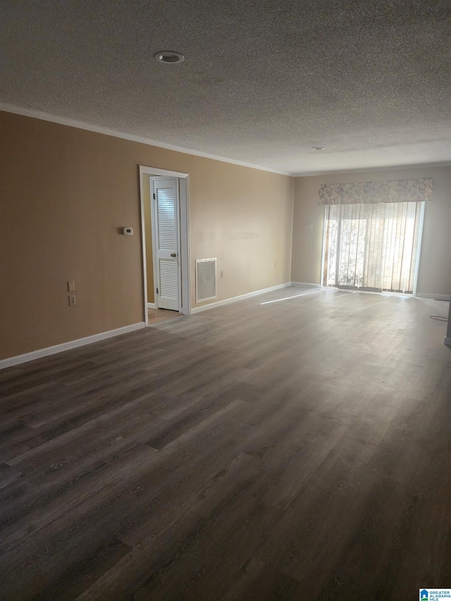 empty room with a textured ceiling, visible vents, baseboards, ornamental molding, and dark wood finished floors