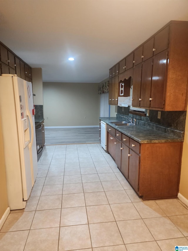 kitchen featuring light tile patterned floors, white appliances, a sink, and decorative backsplash