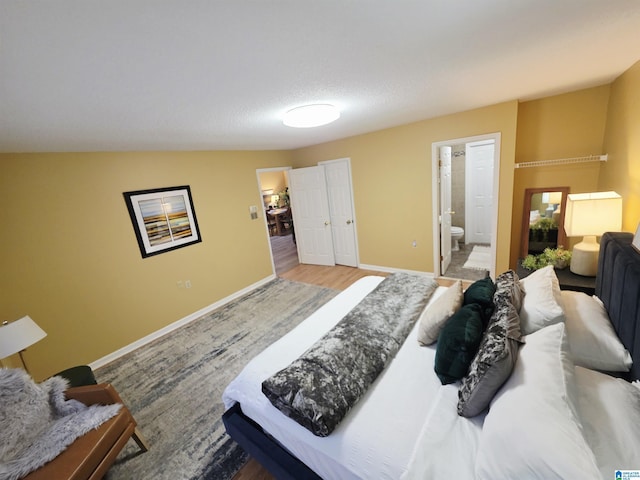 bedroom with wood finished floors, ensuite bathroom, and baseboards