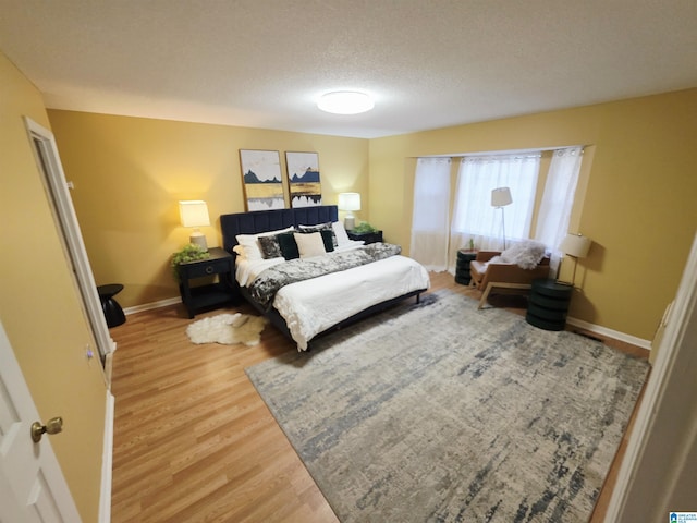 bedroom featuring wood finished floors, a textured ceiling, and baseboards