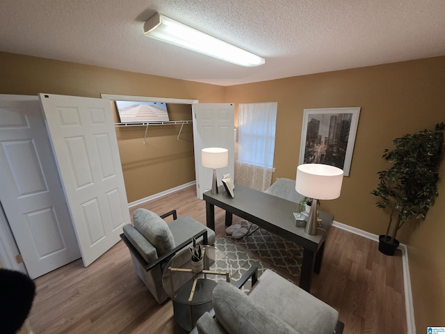office with light wood-type flooring, a textured ceiling, and baseboards