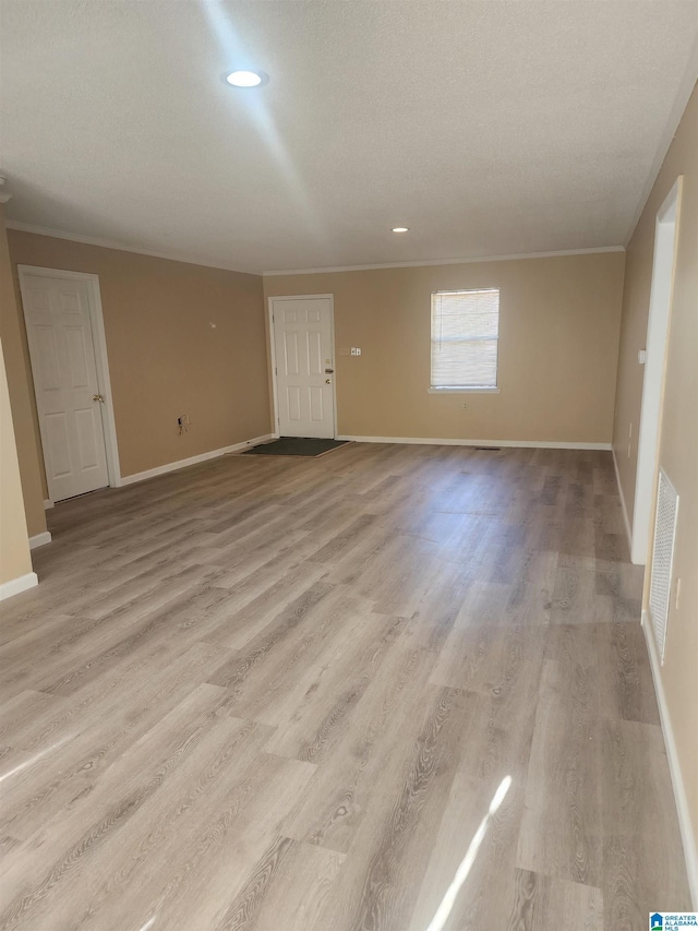 spare room featuring light wood-style floors, visible vents, and baseboards