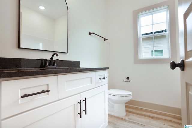 bathroom featuring recessed lighting, toilet, vanity, wood finished floors, and baseboards