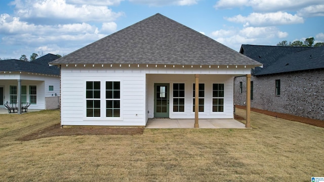 rear view of house with a patio area, a shingled roof, and a lawn