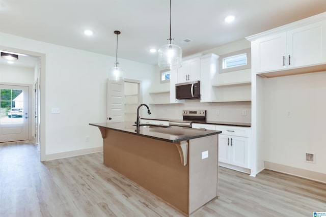 kitchen with an island with sink, stainless steel appliances, white cabinetry, open shelves, and a sink