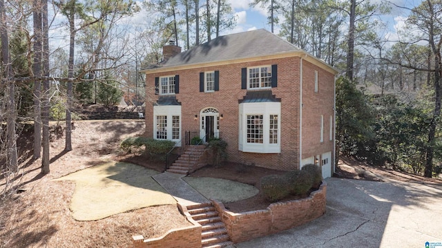 view of front facade with aphalt driveway, french doors, brick siding, a chimney, and a garage