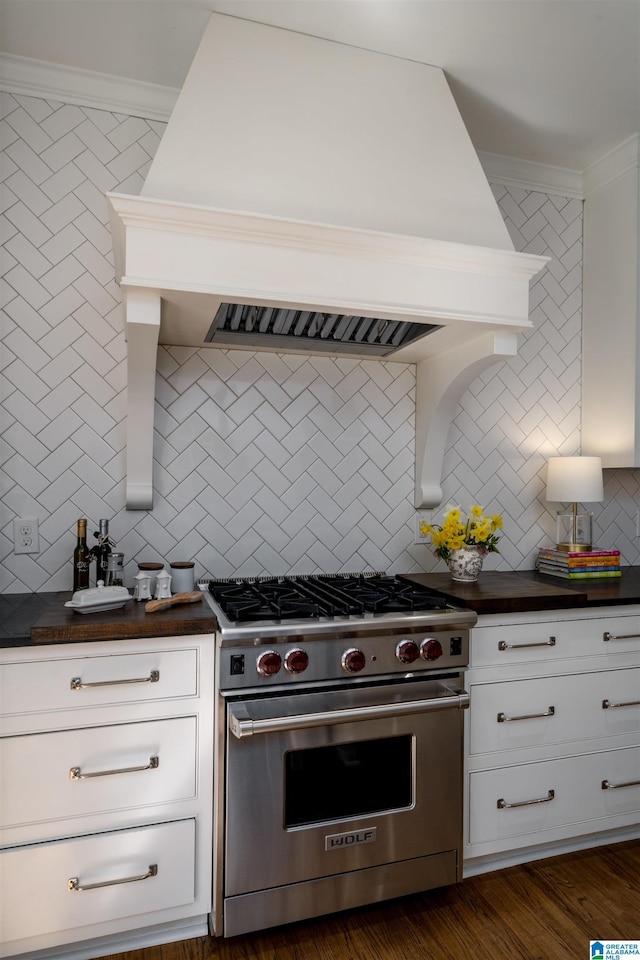 kitchen with crown molding, dark countertops, white cabinetry, premium stove, and premium range hood