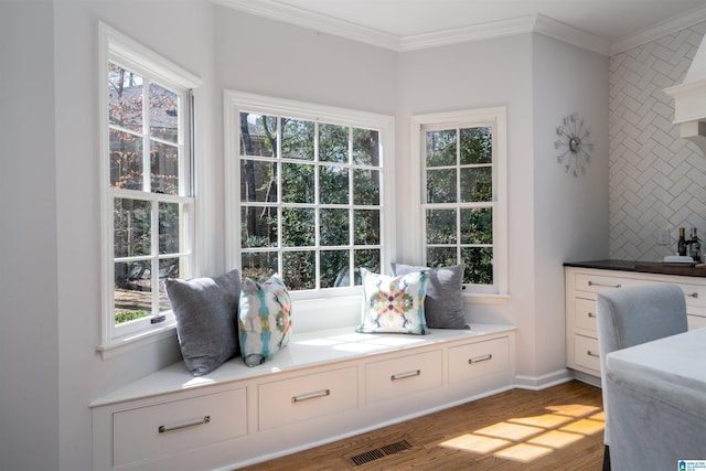 mudroom with a healthy amount of sunlight, wood finished floors, visible vents, and crown molding