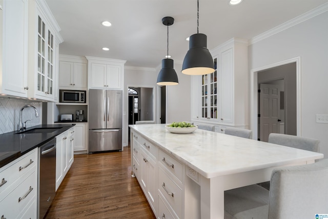 kitchen featuring dark wood finished floors, tasteful backsplash, appliances with stainless steel finishes, ornamental molding, and a sink