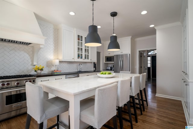 kitchen featuring a breakfast bar area, backsplash, appliances with stainless steel finishes, white cabinets, and premium range hood