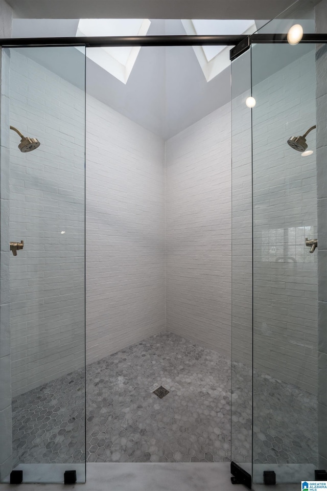 full bath featuring vaulted ceiling with skylight and a tile shower