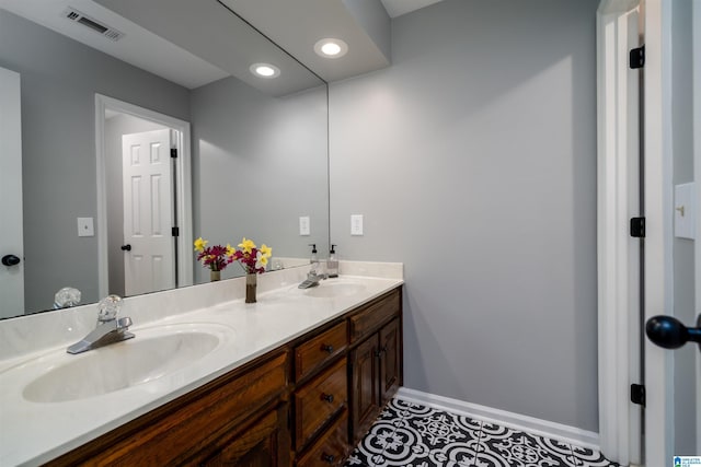 full bathroom with double vanity, baseboards, visible vents, and a sink