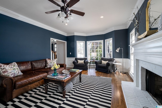 living area with a fireplace, wood finished floors, stairway, wainscoting, and crown molding