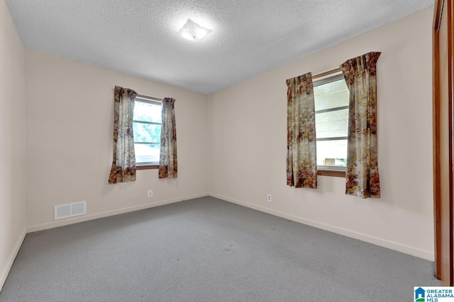 unfurnished room with carpet, visible vents, a textured ceiling, and baseboards