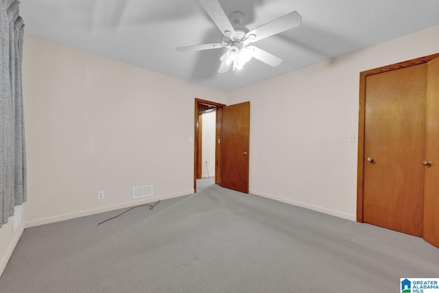 unfurnished room featuring visible vents, light carpet, ceiling fan, a textured ceiling, and baseboards