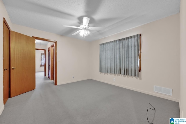 spare room with light carpet, attic access, visible vents, a ceiling fan, and a textured ceiling