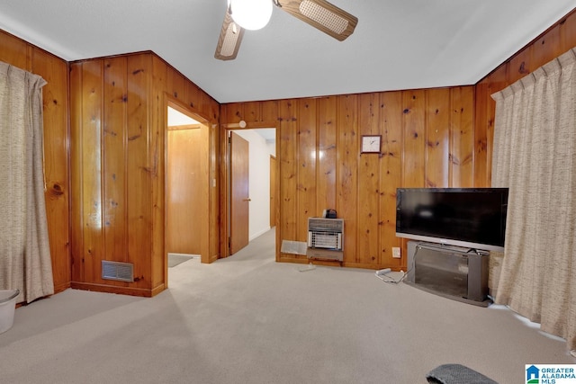 living area featuring heating unit, visible vents, a ceiling fan, light carpet, and wooden walls